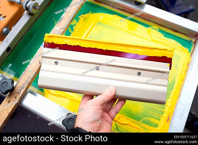 Squeegee for Serigraphy silk screen print process at clothes factory. Frame, squeegee and plastisol color paints