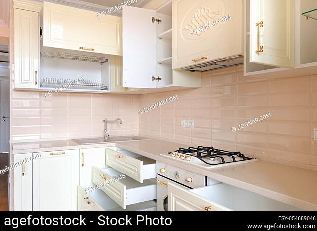 Modern classic spacioius cream colored kitchen, some drawers and trays are open