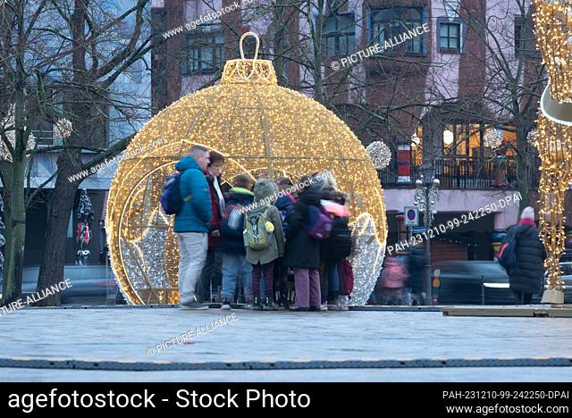 07 December 2023, Magdeburg: Teachers and pupils walk across the cathedral square with the Christmas sculptures of the Magdeburg World of Lights in rainy...