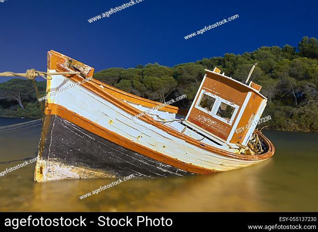 night scene of an abandoned and sunken fishing boat on the coast of Cadiz. Andalusia, Spain