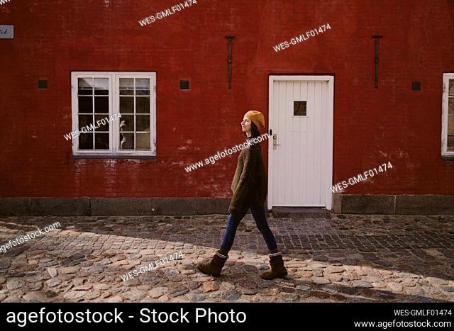 Woman walking on cobblestone street by building