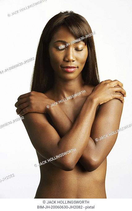 Nude African woman covering breasts