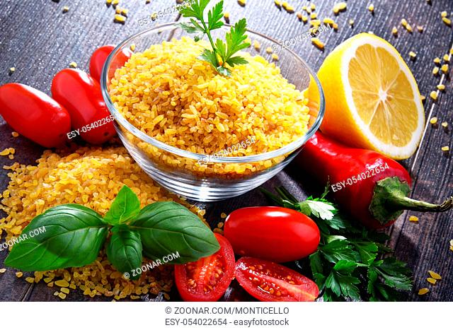 Bowl of uncooked bulgur on wooden table