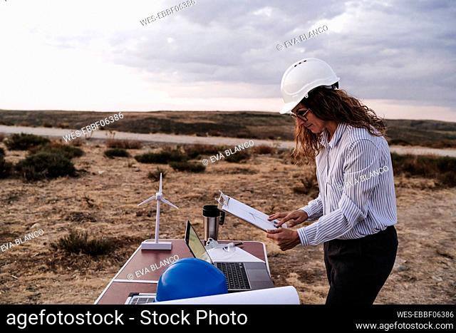 Engineer holding clipboard working at desk at wind farm