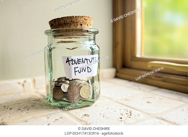 Wales, Monmouthshire, Monmouth. Glass jar labelled Adventure Fund containing loose change