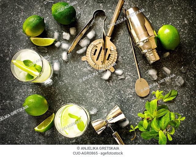Mojito cocktail with lime and mint in glass on a stone table. Bar tools and ingredients for cocktail. Top view