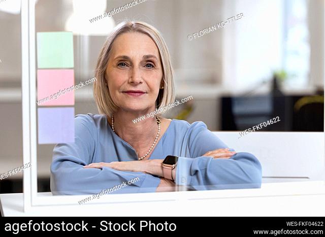 Blond businesswoman with arms crossed behind glass