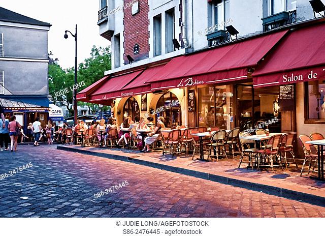 Outdoor Cafe on Rue du Mon Cenis, in the Montmarte Section of Paris, France. People dining and enjoying the surrounding artsy view