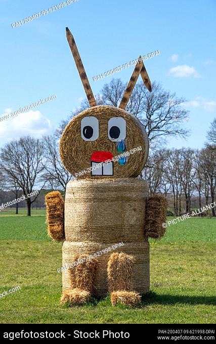 07 April 2020, Lower Saxony, Steinbrink: An Easter bunny made of straw with tears in his eyes is standing in a field. Due to the worldwide corona eruption
