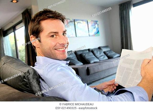 Man relaxing in sofa with newspaper