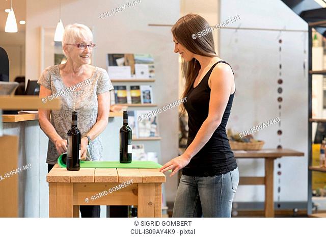Woman at table with bottles of wine smiling