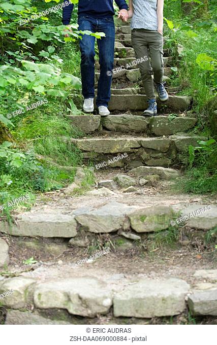 Couple walking down stone steps in woods