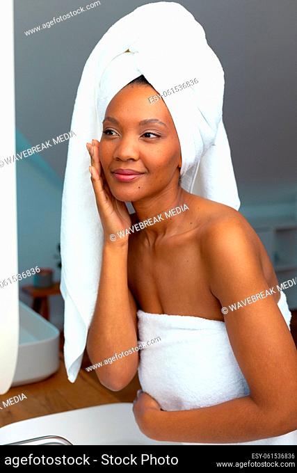 Young african american woman wrapped in towel feeling confident of her skin in bathroom, copy space