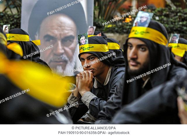 10 September 2019, Lebanon, Beirut: Supporters of Hezbollah, the Shia pro-Iranian political party and militant group, sit next to a poster of Ayatollah Khomeini