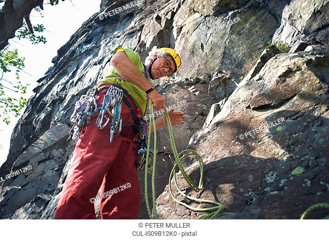 Low angle view of rock climber preparing climbing rope