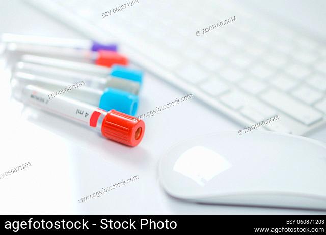 Close up Medicine bottles for samples next to computer keyboard and mouse in medicine, closeup on white background