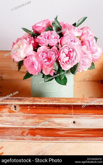 florist did rich bunch flowers light background, wooden surface. green vase