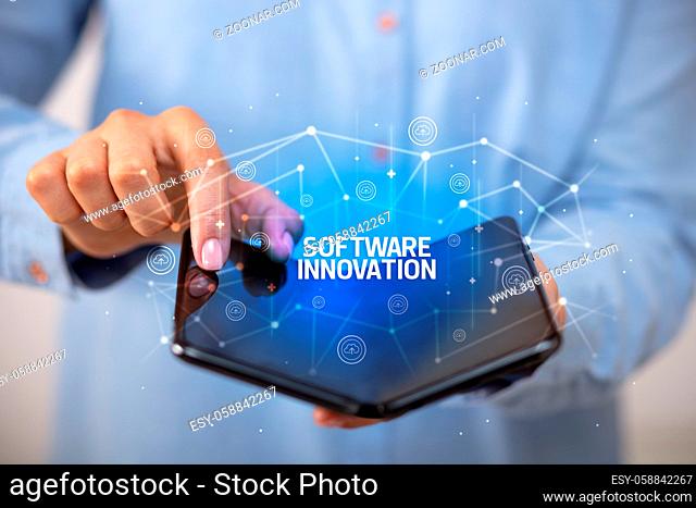 Businessman holding a foldable smartphone with SOFTWARE INNOVATION inscription, new technology concept