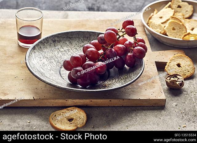 Still life with red grapes, walnuts, bread chips and red wine