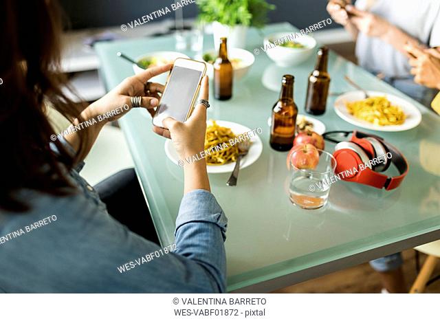 Close-up of friends sitting at table using cell phones