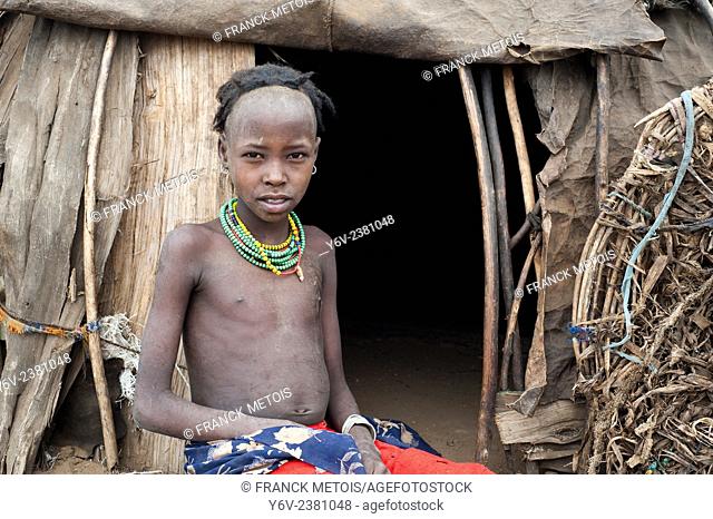 Girl belonging to the Dhasanech tribe in front of a hut ( Omo valley, Ethiopia)