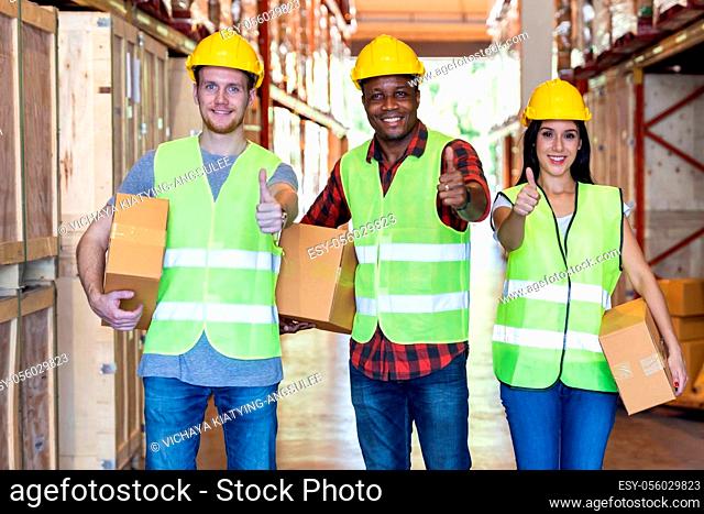 Portrait of caucasian white and african black warehouse workers hold cardboard box packaging in warehouse distribution center environment