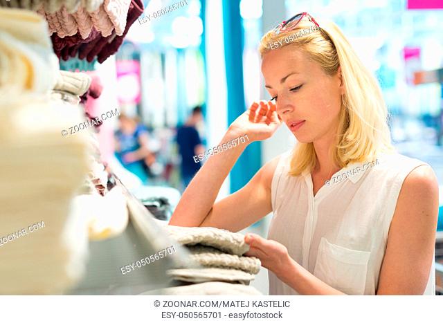 Pretty, young woman choosing the right towel for her apartment in a modern home decor furnishings store