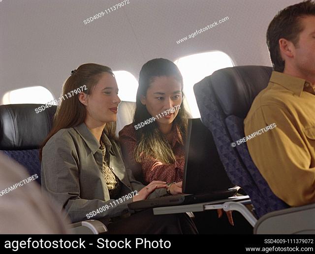 Young women using laptop on airplane