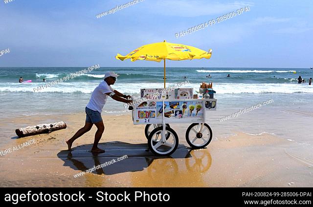 13 August 2020, France, Marseillan: An ice-cream vendor pushes his van along the beach in Marseillan Plage. Photo: Waltraud Grubitzsch/dpa-Zentralbild/ZB