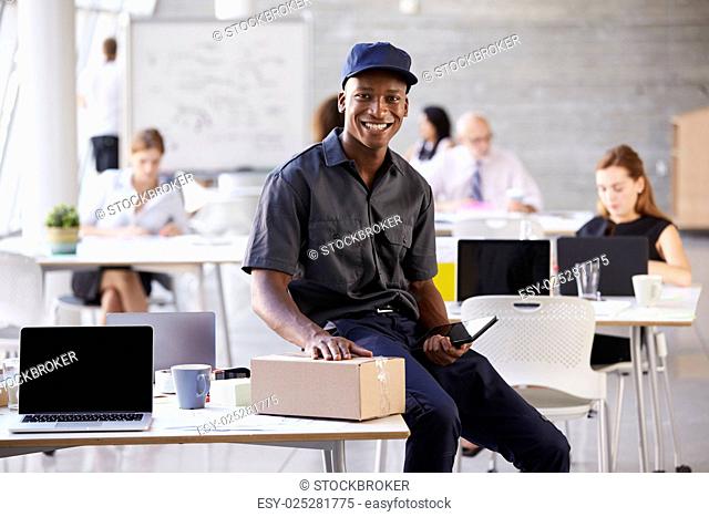 Portrait Of Courier Collecting Package From Busy Office