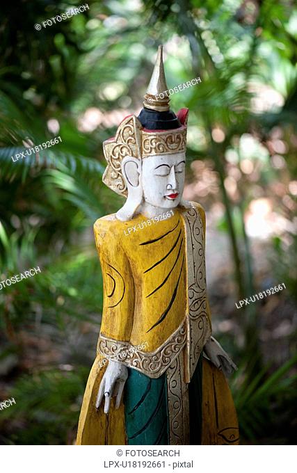 Wooden asian statue with ornate headpiece and large earlobes
