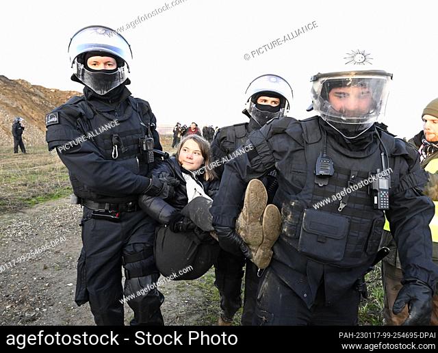 17 January 2023, North Rhine-Westphalia, Erkelenz: Police officers carry Swedish climate activist Greta Thunberg (M) out of a group of protesters and activists...