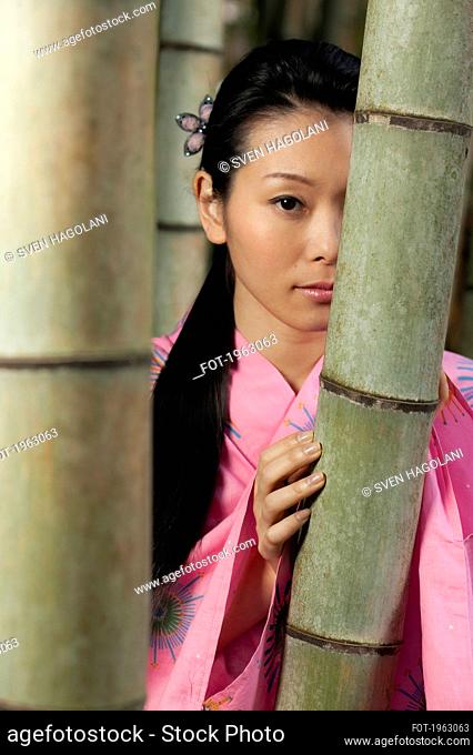 Portrait beautiful young woman in pink kimono at bamboo trees