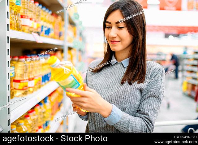 Woman choosing sunflower oil in a supermarket, family shopping. Female customer in shop, buyer in market