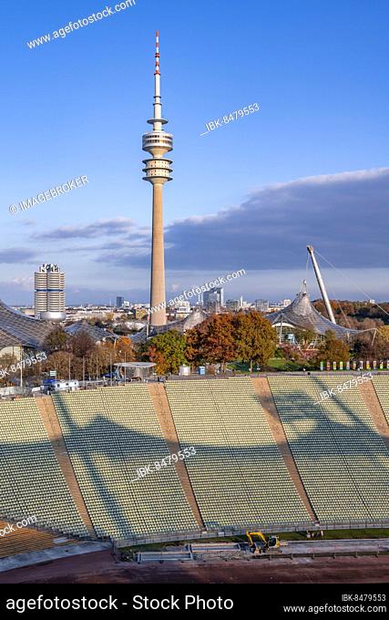 Rows of seats in the Olympic Stadium, BMW four-cylinder and Olympic Tower with tent roof of the Olympic swimming hall, in autumn, Olympic Park, Munich, Bavaria