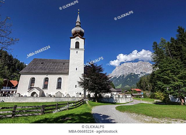 Typical church of alpine village surrounded by peaks and woods Garmisch Partenkirchen Oberbayern region Bavaria Germany Europe