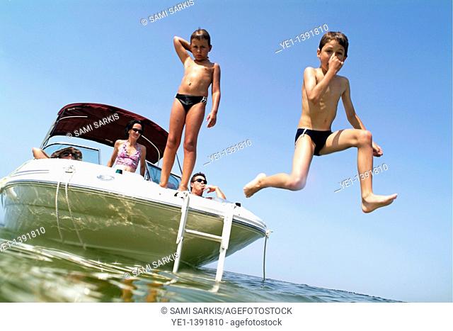 Two young boys jumping from a boat into the sea near Biscarrosse, Bordeaux, France