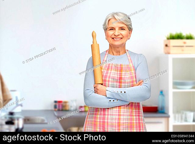 smiling senior woman with rolling pin at kitchen