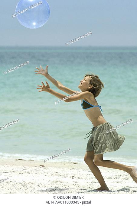 Girl catching beach ball on beach