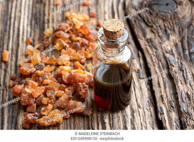 A bottle of myrrh essential oil and resin on a wooden background