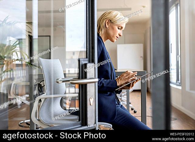 Blond businesswoman using tablet in conference room