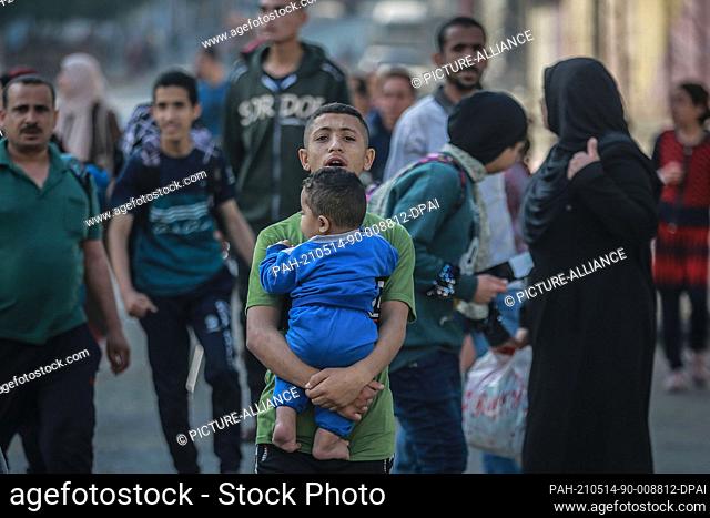 14 May 2021, Palestinian Territories, Gaza City: Palestinians flee from their houses in the Shejaiya neighbourhood during an Israeli airstrike on Gaza City amid...