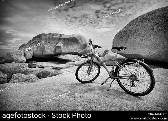 parked mountain bike in front of felsformatiionem, ãžle renote, rocky coast along the sentier des douaniers, trégastel, côte de granit rose, cotes d'armor