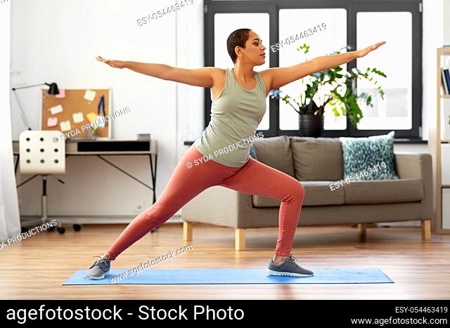 african woman doing yoga warrior pose at home