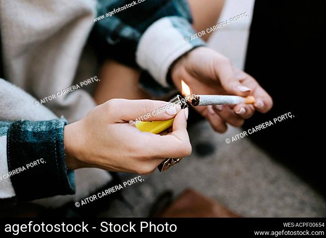 Close-up of a woman's hands lighting a marijuana joint
