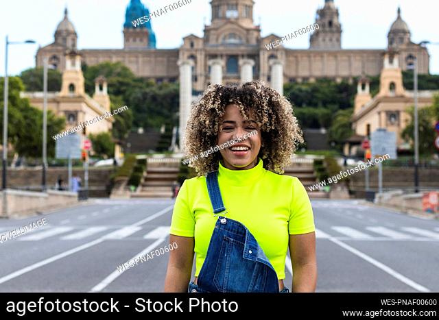 Cheerful woman standing on street against buildings in city