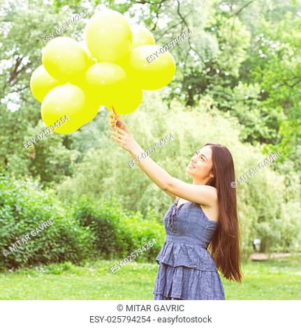 Happy, Freedom, Carefree Young Woman with Yellow Balloons at beautiful Summer Day Outdoor. Attractive female enjoying nature