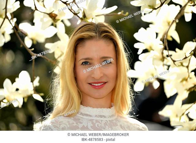 Blonde, portrait in front of a blooming magnolia tree, Baden-Württemberg, Germany