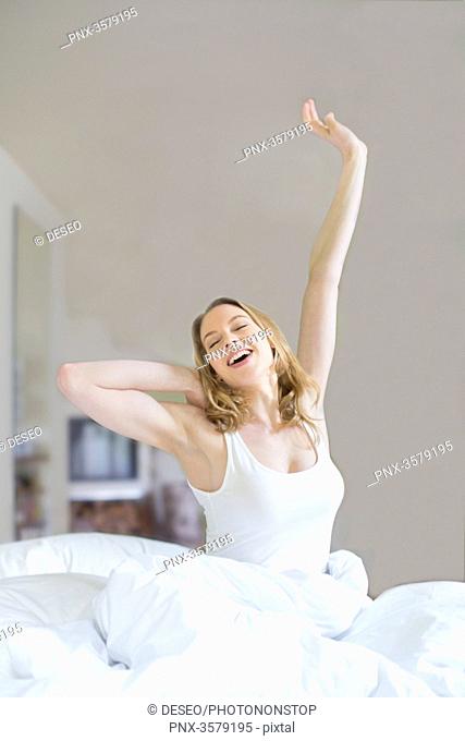 Pretty blonde woman stretching in bed in the morning