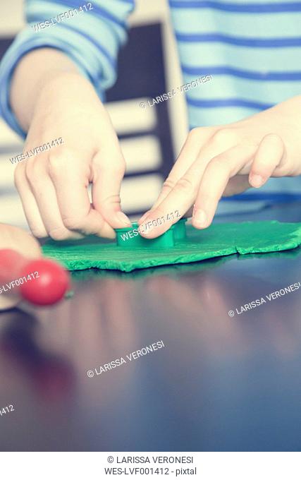 Little girl playing with green modeling clay